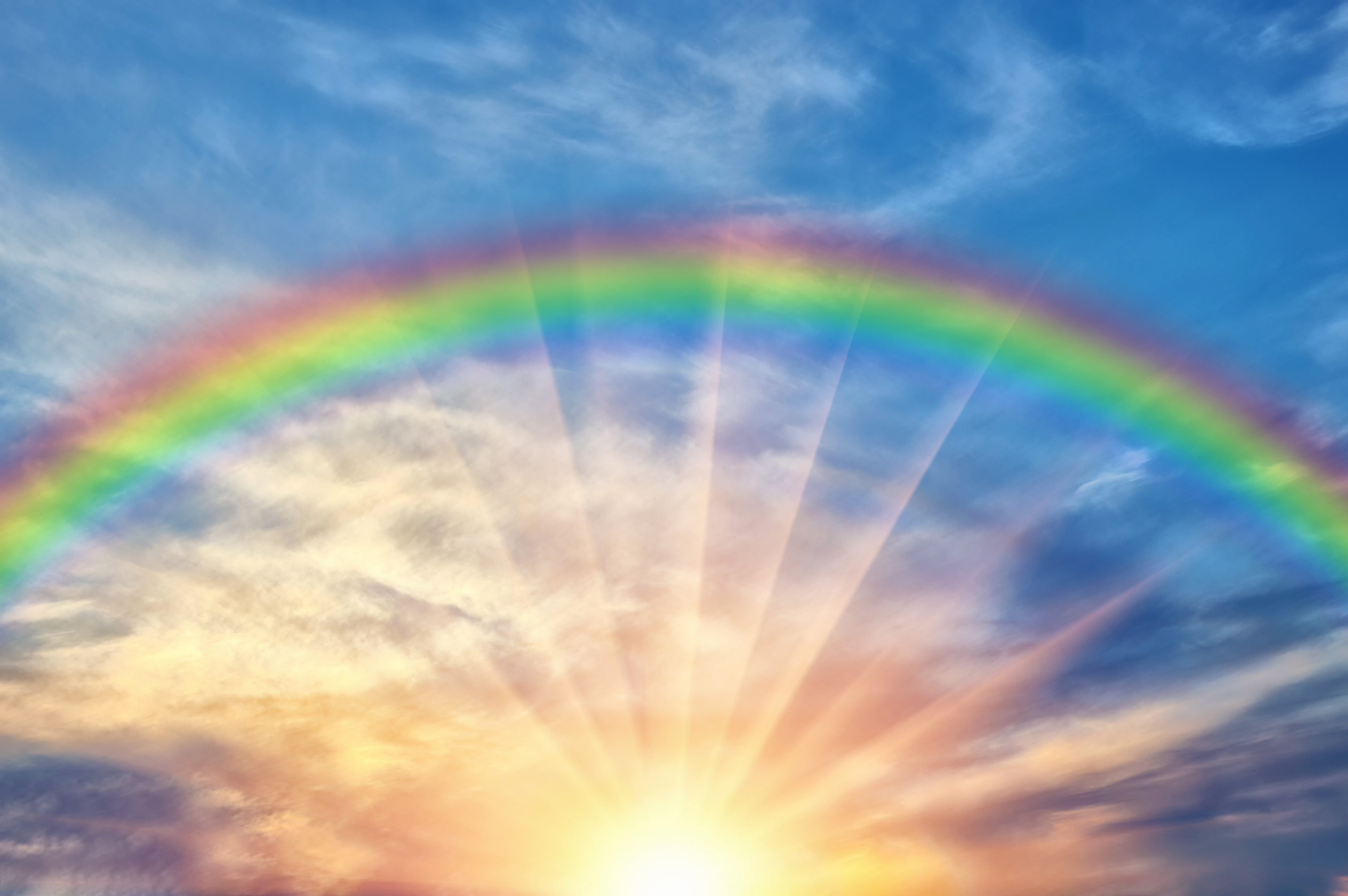 rainbow against blue sky with the sun 