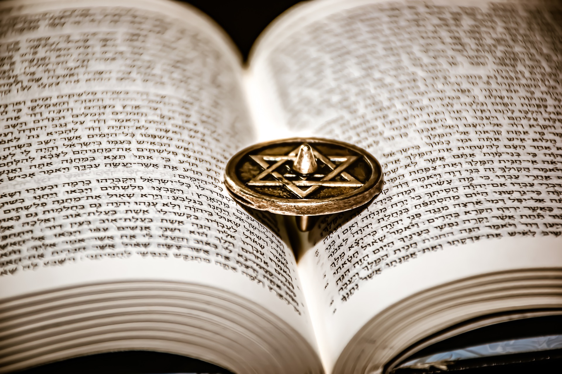 an open copy of the Tora with a golden star of david on circular black book mark